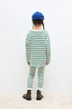 Niña vistiendo el conjunto de mallas y camiseta de rayas verdes de Weekend House Kids, vista atrás.