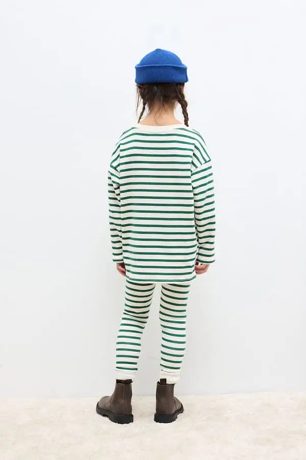 Niña vistiendo el conjunto de mallas y camiseta de rayas verdes de Weekend House Kids, vista atrás.