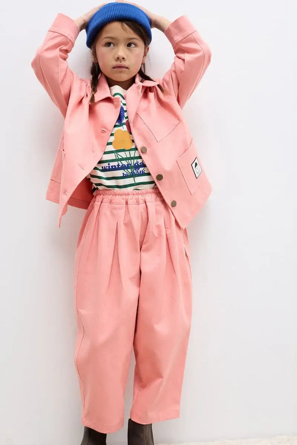 Niña vistiendo pantalones coral y chaqueta coral de Weekend House Kids 