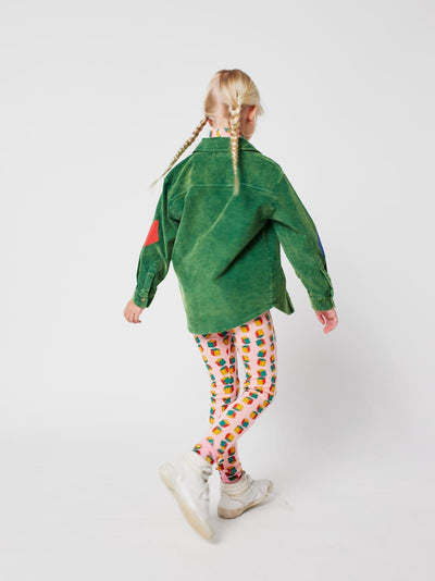 Niña vistiendo mallas rosas con estampado de dados y camisa verde de Bobo Choses.