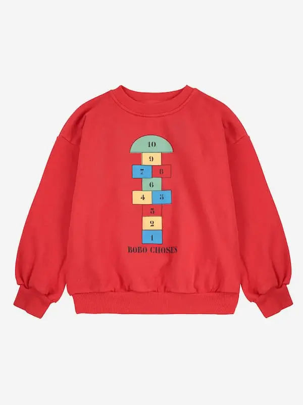 Sudadera roja con dibujo de rayuela y logo de Bobo Choses en la parte delantera.