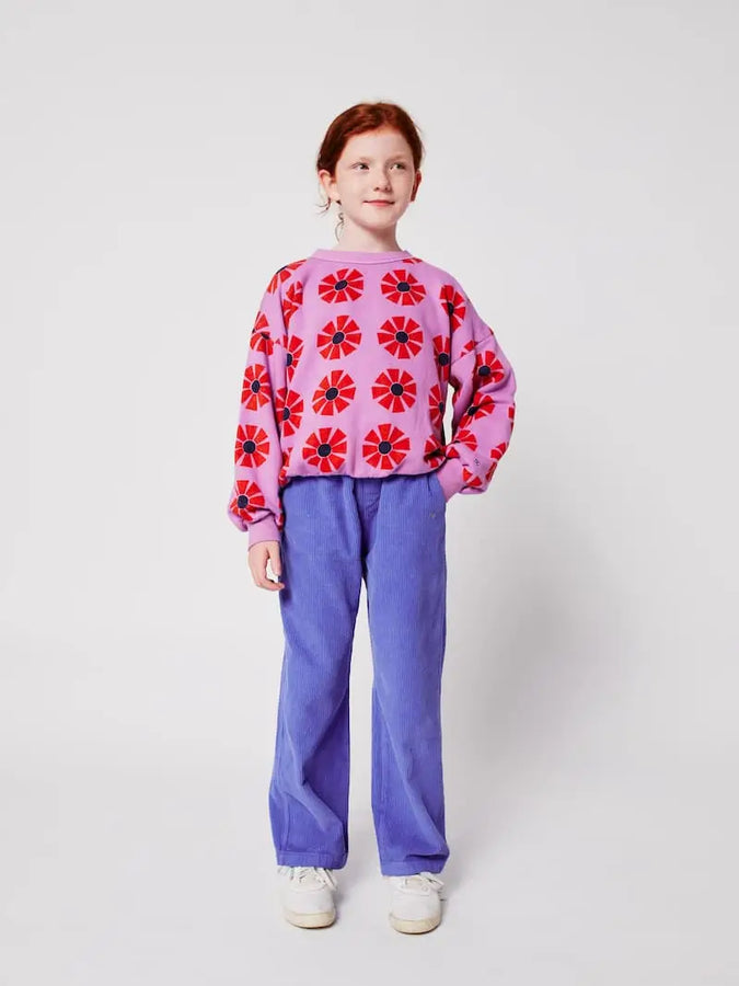 Niña con sudadera morada de Bobo Choses con caleidoscopios estampados de color rojo, conjuntado con un pantalón azul océano