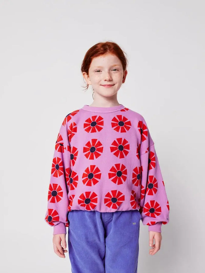 Primer plano de niña con sudadera morada de Bobo Choses con caleidoscopios estampados de color rojo, conjuntado con un pantalón azul océano