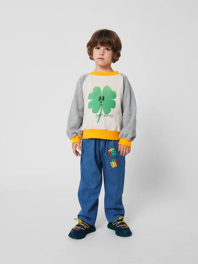 Niño vistiendo pantalones azules con dibujo de dados y sudadera color block con trébol.