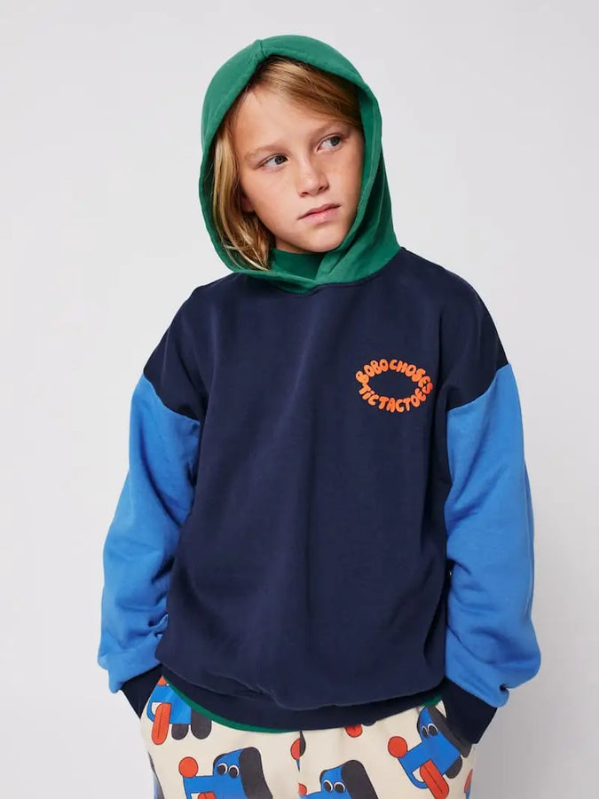 Niño vistiendo la sudadera color block con capucha y pantalones jogging con estampado de perros.