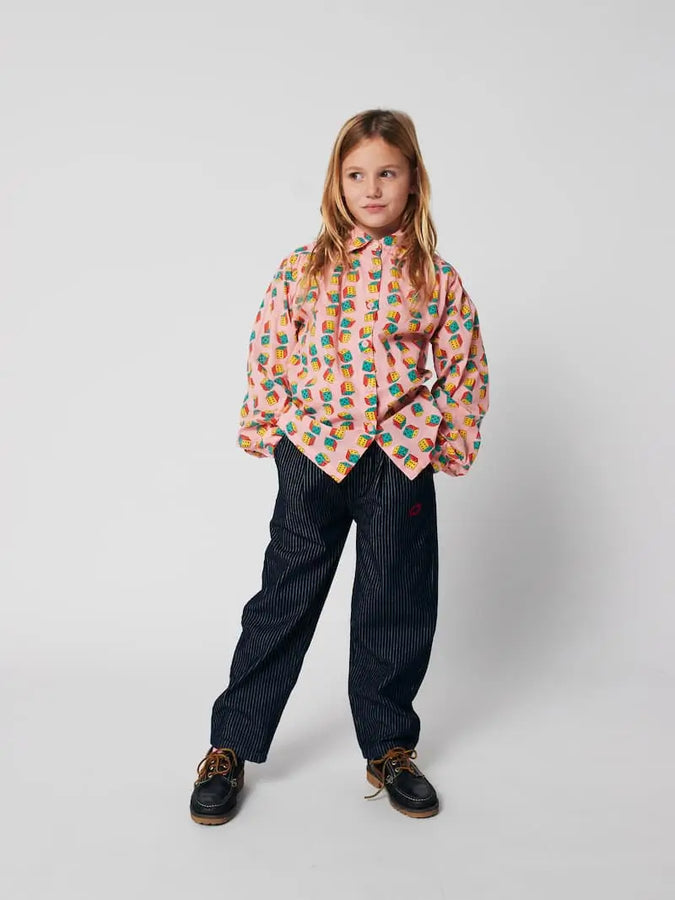 Niña vistiendo camisa con estampado de dados y pantalones vaqueros de Bobo Choses.