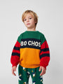 Niño con jersey color block rojo, verde, azul marino y amarillo con logo de Bobo Choses en el pecho.