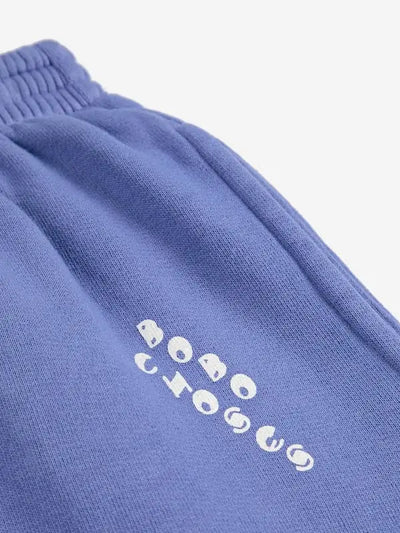 Detalle de logo de Bobo Choses en bolsillo izquierdo en los pantalones jogging de color morado para niñas y niños.