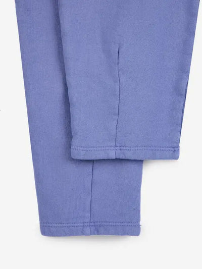 Detalle de costura en los tobillos sin goma de los pantalones jogging de Bobo Choses de color morado para niñas y niños.