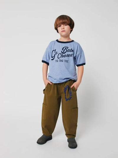 Niño con camiseta azul y  pantalones verdes de Bobo Choses. 