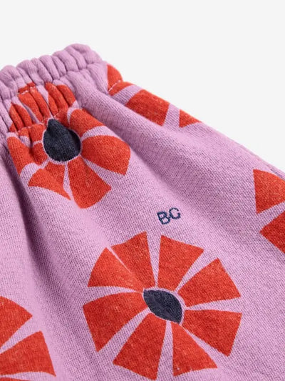 Detalle de logo de BC bordado en falda corta de color morado con estampado de caleidoscopios rojos