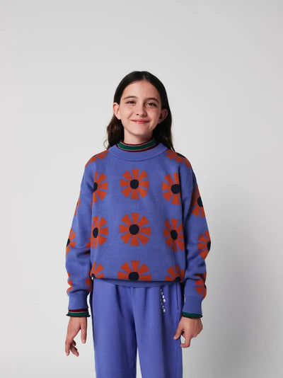 Niña con jersey morado con estampado de caleidoscopios rojos para niñas y niños de Bobo Choses con pantalones morados de jogging a juego con logo en bolsillo izquierdo.