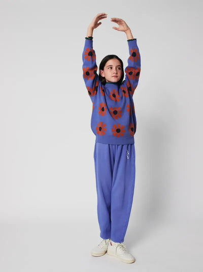 Niña con jersey morado con estampado de caleidoscopios rojos de Bobo Choses con pantalón jogging morado a juego.