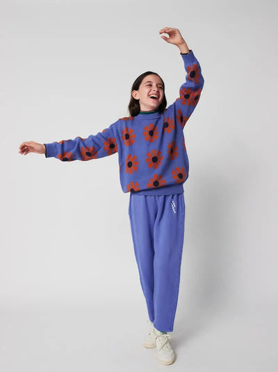 Niña con jersey morado con estampado de caleidoscopios rojos de Bobo Choses con pantalón jogging morado a juego.