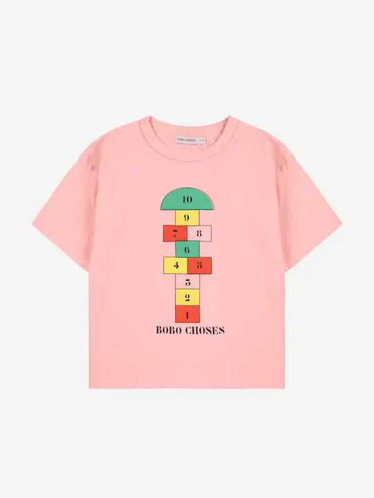 Camiseta rosa con dibujo de rayuela y logo de Bobo Choses en la parte delantera.