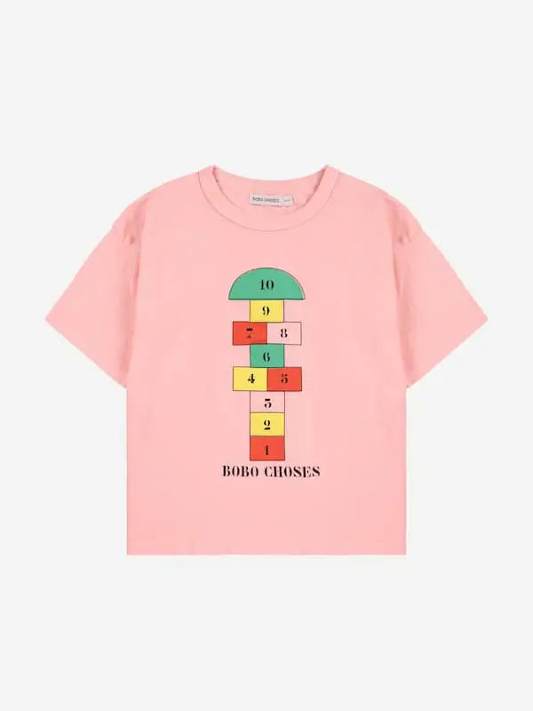 Camiseta rosa con dibujo de rayuela y logo de Bobo Choses en la parte delantera.