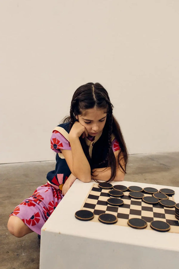 Niña con vestido de caleidoscopios y chaleco azul, todo de Bobo Choses.