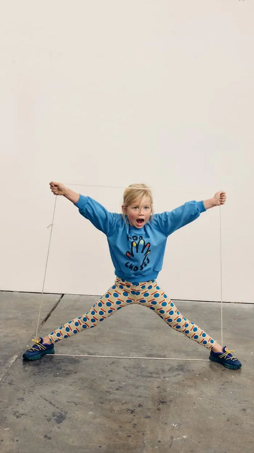Niña vistiendo la sudadera azul High Five y mallas multicolores de Bobo Choses.
