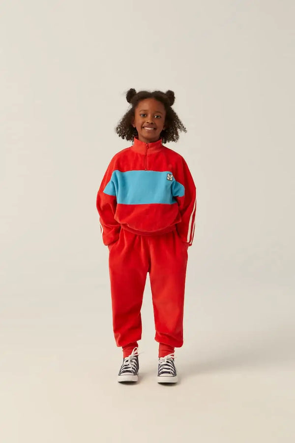 Niña con sudadera roja de terciopelo y pantalones chandal rojos de marca infantil sostenible The Campamento.