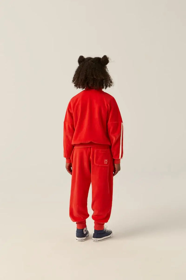 Vista atras de niña con conjunto rojo de terciopelo, sudadera y pantalon chandal, de The Campamento.