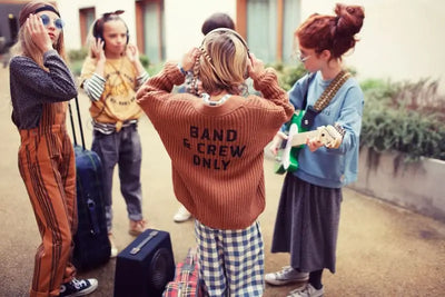 Grupo de niñas y niña con cárdigan marrón de punto con botones de Piupiuchick y texto estampado “Band & Crew Only” - parte trasera