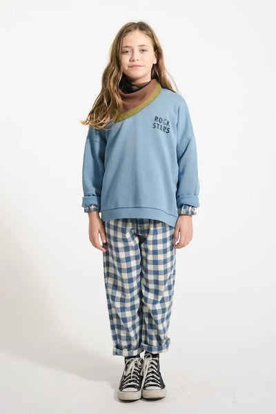 Niña con pantalones de cuadros azules y blancos y sudadera azul con texto "Rock stars" de Piupiuchick.