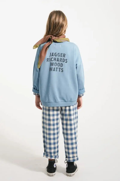 Niña con pantalón de cuadros y sudadera azul de Piupiuchick, vista trasera.