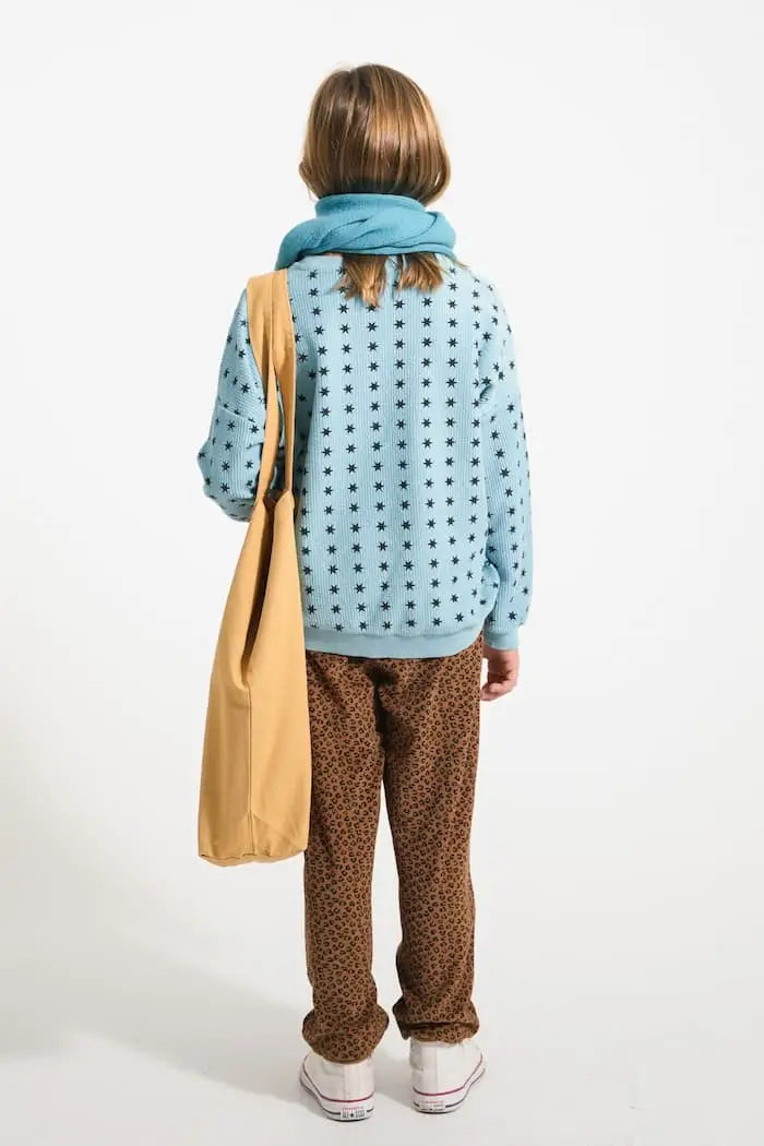 Niña con sudadera azul con estrellas negras y jogging marrón con estampado de animal print de Piupiuchick.