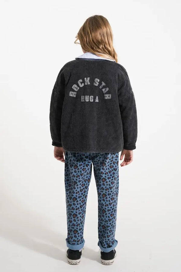 Niña con pantalones de pana con estampado de animal print y chaqueta negra acolchada de Piupiuchick, vista trasera.