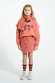 Niña con falda rosa de flores, sudadera rosa Groupie y calcetines burdeos Piupiuchick.