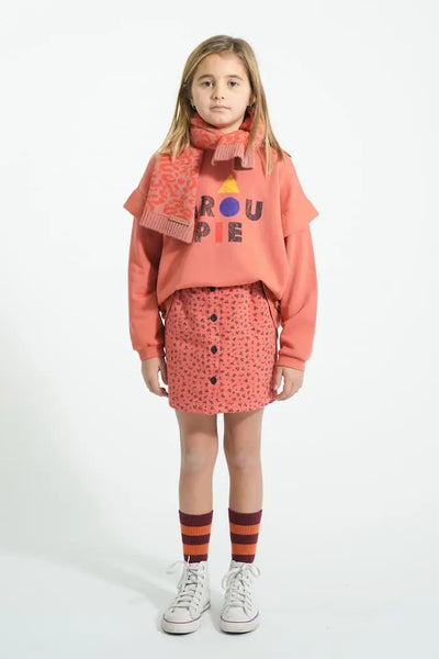 Niña con falda rosa de flores, sudadera rosa Groupie y calcetines burdeos Piupiuchick.