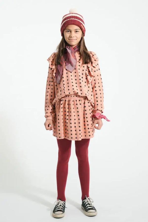 Niña con sudadera rosa con volantes y estampado de estrellas negras y falda rosa con estrellas negras, Piupiuchick aw25 moda sostenible