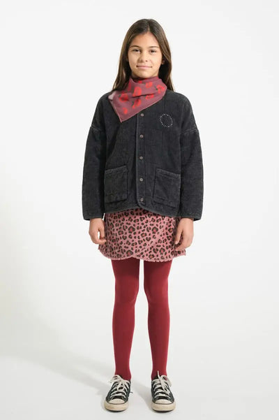 Niña con falda de pana con animal print y chaqueta negra acolchada de Piupiuchick. vista delantera.