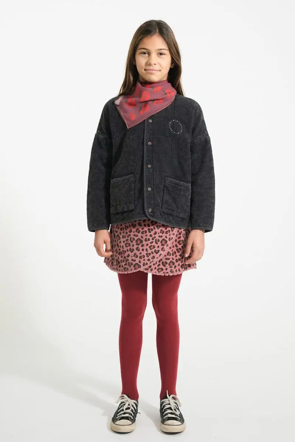 Niña con falda de pana con animal print y chaqueta negra acolchada de Piupiuchick. vista delantera.