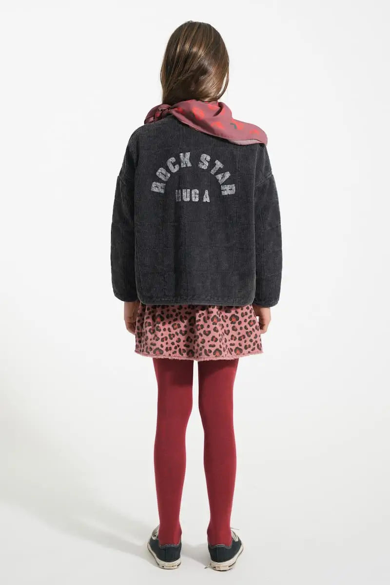 Niña con falda rosa de animal print y chaqueta negra colchada, Piupiuchick, vista trasera.
