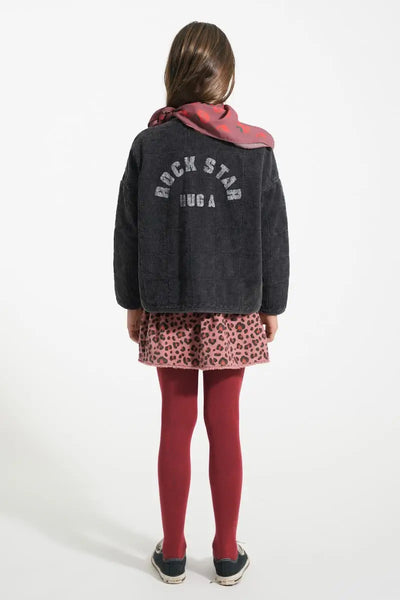 Niña con falda rosa de animal print y chaqueta negra colchada, Piupiuchick, vista trasera.