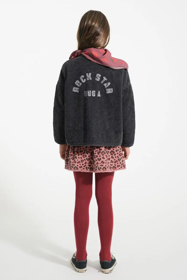 Niña con falda rosa de animal print y chaqueta negra colchada, Piupiuchick, vista trasera.