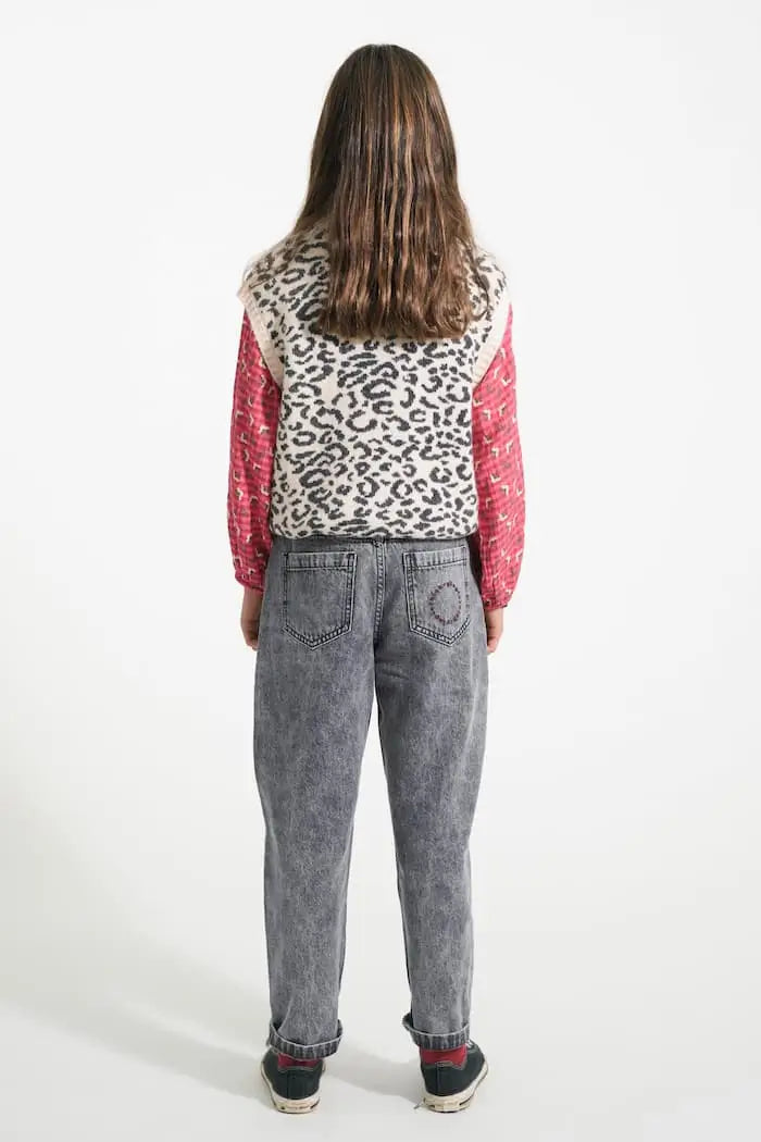Niña con vaqueros mom fit negros, blusa rosa y chaleco de animal print de Piupiuchick, vista atrás.