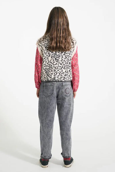 Niña con vaqueros mom fit negros, blusa rosa y chaleco de animal print de Piupiuchick, vista atrás.