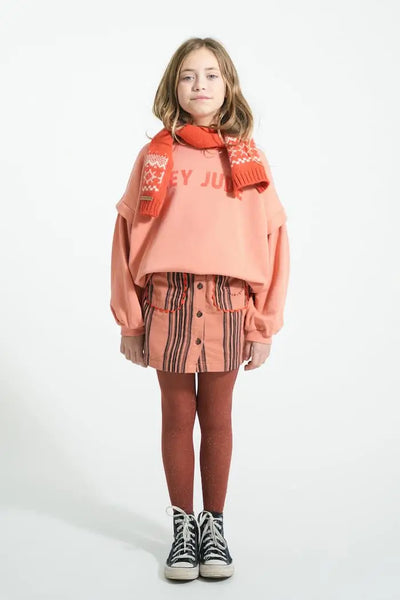 Niña con falda rosa de rayas y sudadera rosa con texto "hey Jude" en la parte delantera, Piupiuchick