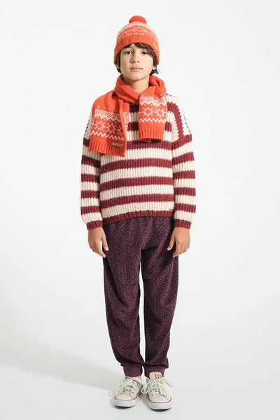 Niño con jersey de rayas crudo y burdeos, pantalón jogging de animal print, bufanda y gorro de color rojo, todo de Piupiuchick.