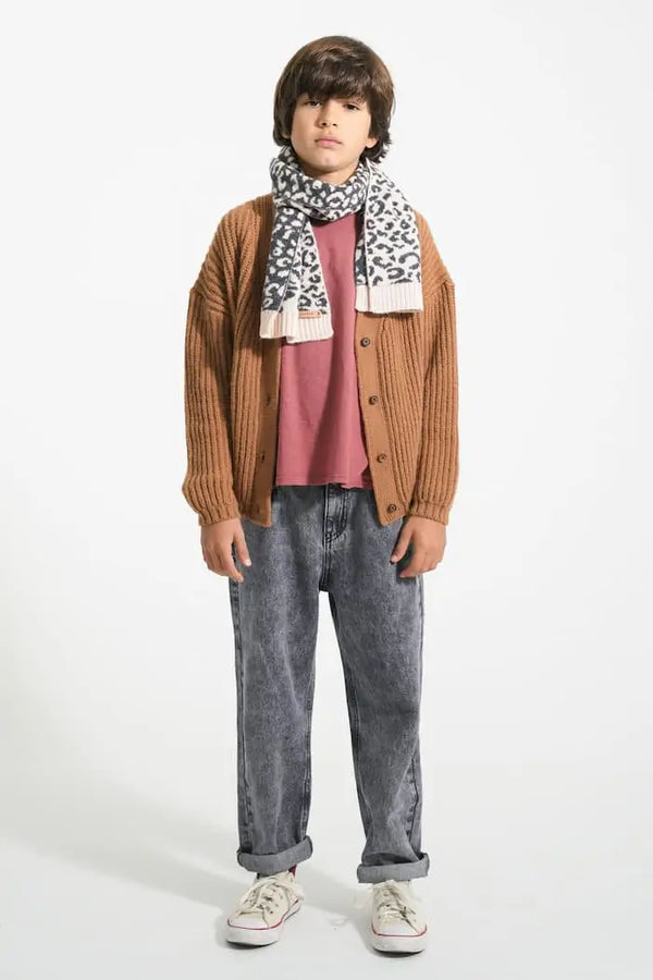 Niño con cárdigan marrón de punto con botones de Piupiuchick y estrella pequeña estampada en negro en el lado izquierdo - parte delantera, camiseta burdeos y vaqueros unisex negros.