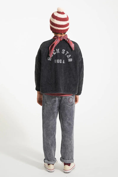 Niño con vaqueros negro, chaqueta negra y gorro de rayas de color burdeos y crudo de Piupiuchick.