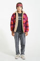 NIño con vaqueros unisex grises, sudadera negra JImi Hendrix y chaqueta de cuadros multicolor.