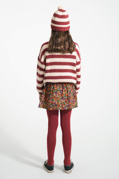 Niña vista atras con falda corta multicolor de flores, gorro de rayas y jersey de rayas de Piupiuchick