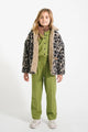 Niña vistiendo pantalones verdes de cuadros, camisa con cuello Peter Pan de cuadros y chaqueta de animal print, todo de Piupiuchick.