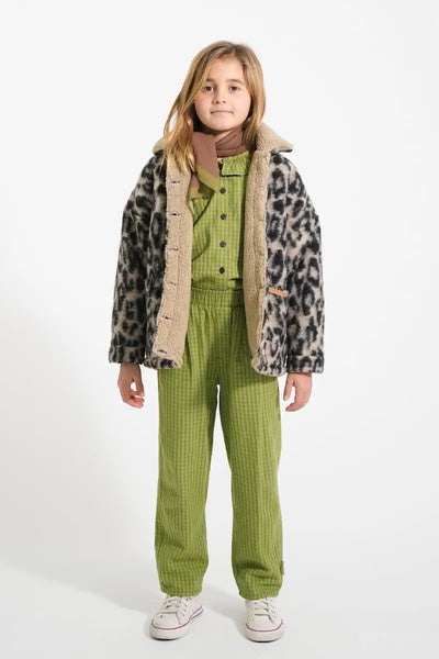 Niña vistiendo pantalones verdes de cuadros, camisa con cuello Peter Pan de cuadros y chaqueta de animal print, todo de Piupiuchick.