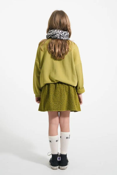 Vista atrás de niña con sudadera caqui y falda corta caqui con flores negros de Piupiuchick.