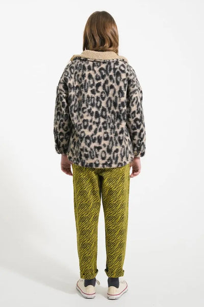 Niña vistiendo el pantalón mom fit caqui con estampado negro de zebra y chaqueta de animal print.