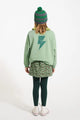 Vista trasera de niña con falda verde de animal print y sudadera verde de Piupiuchick.